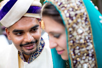 Close up portrait of a bride and groom dressed in ornate colorful Pakistani wedding attire.