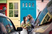 colorful candid photo of bride and groom laughing together in front of a wall of colorful doors in Lancaster City, PA