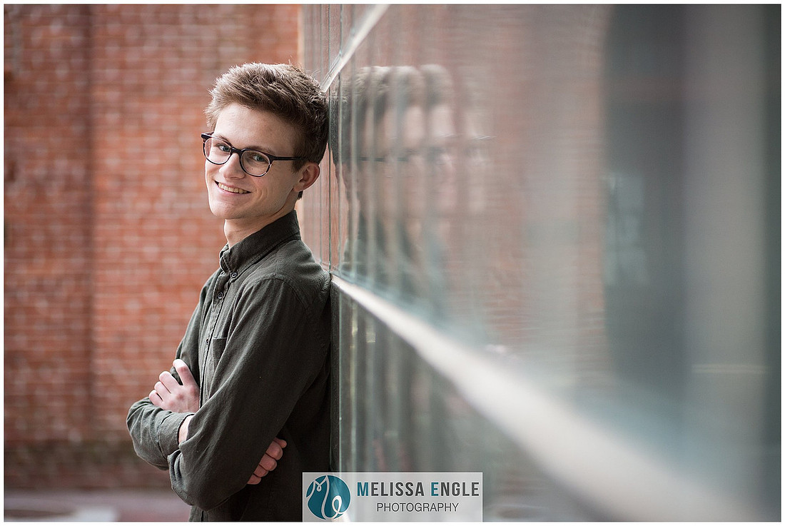 Creative senior portrait of a guy wearing glasses in an urban setting in downtown Lancaster City.