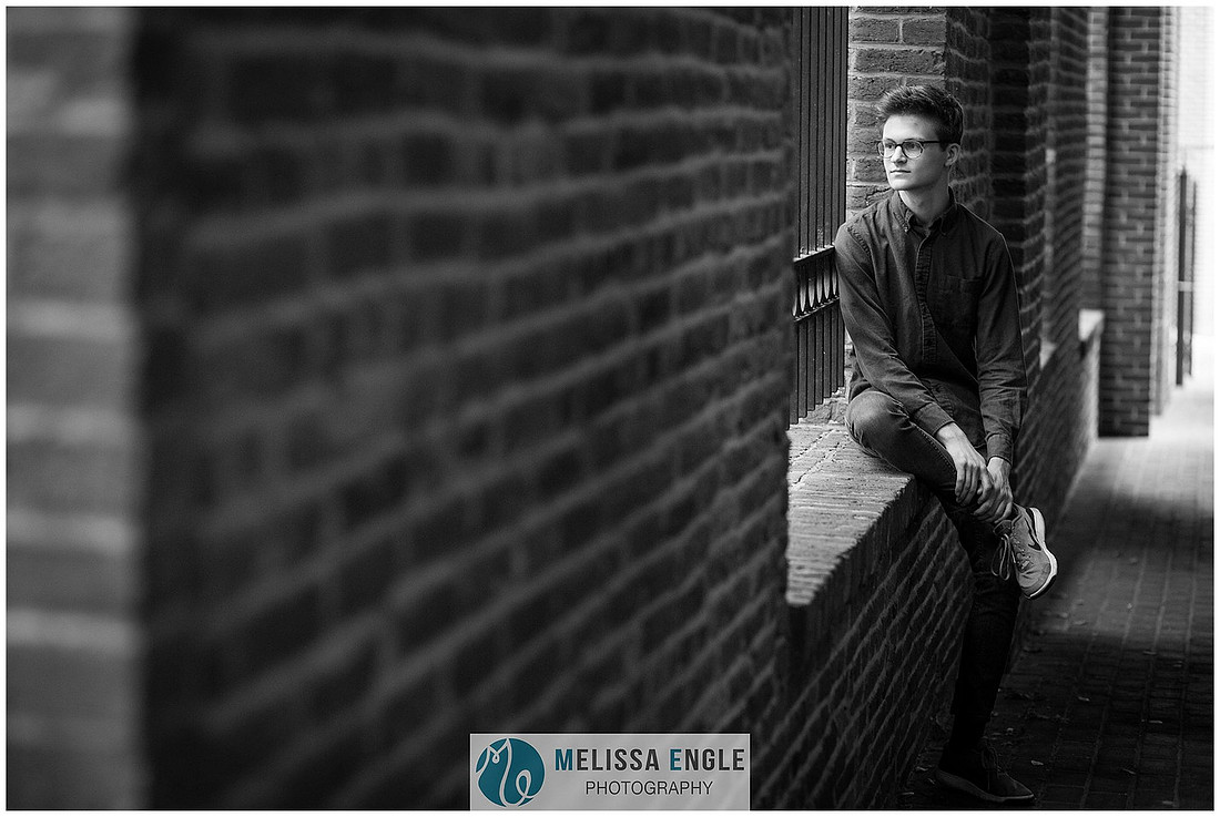 Creative senior portrait of a guy wearing glasses in an urban setting in downtown Lancaster City.