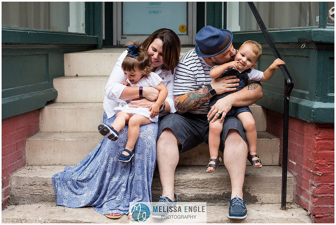 candid photo of a family with twins sitting on steps tickling each other in downtown Lancaster City, PA by Melissa Engle Photography.