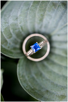 Close up photo of a blue sapphire engagement ring sitting on a leaf