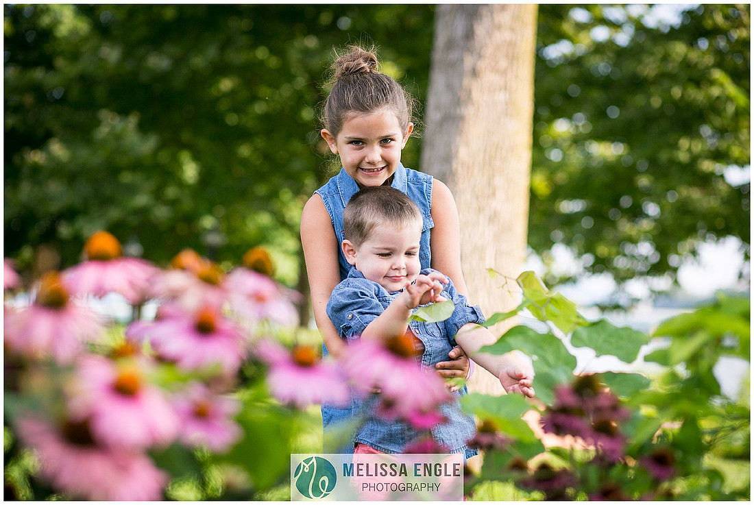 Photo of a brother and sister standing behind some purple echinacea flowers on City Island in Harrisburg, PA