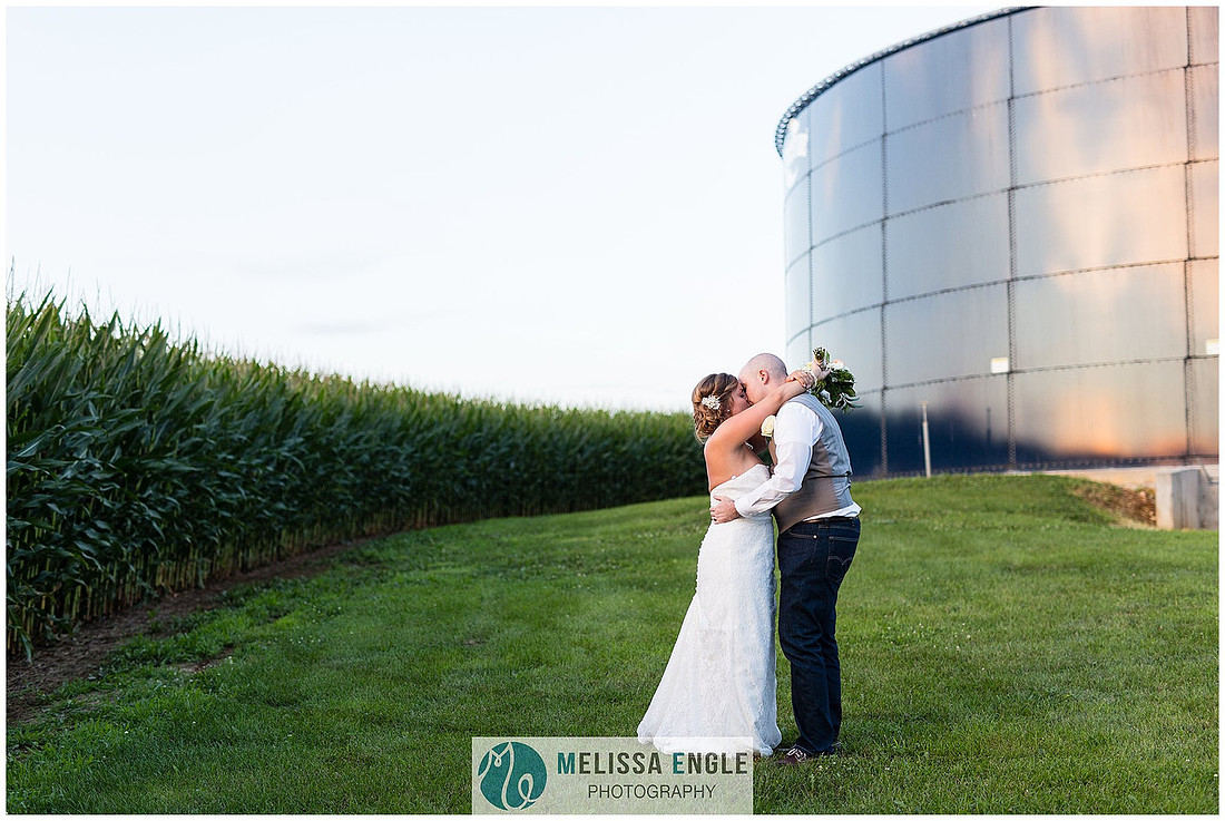 Photo of a bride and groom kissing in front of a corn field and a blue silo at Springside Barn in East Earl, PA.
