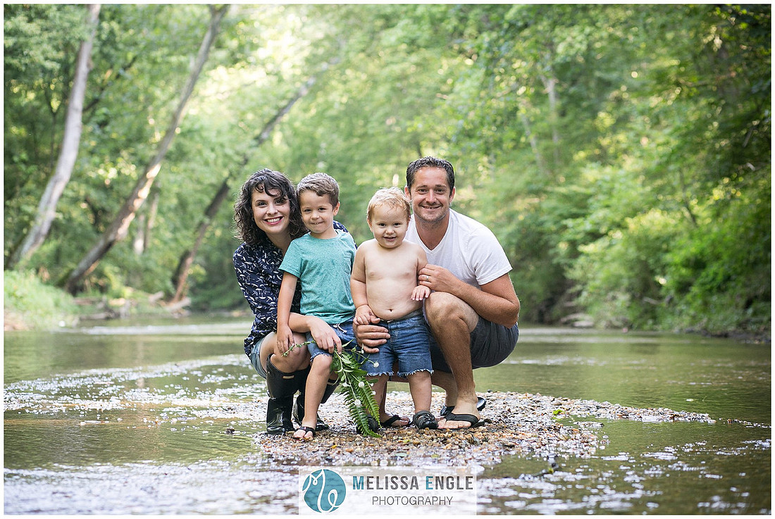Photo of a family with two little boys, smiling and standing in a creek in Lancaster, PA.