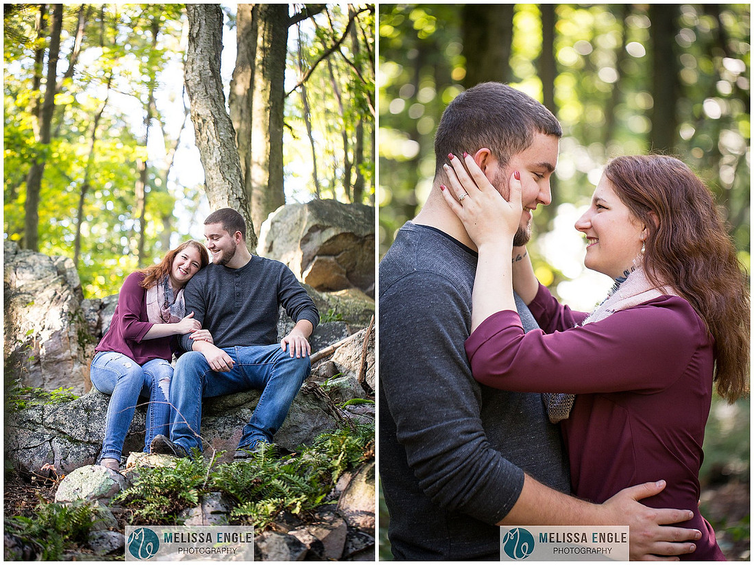 Engagement photo of a couple in the middle of the woods surrounded by trees, rocks and sunlight at Money Rocks County Park.