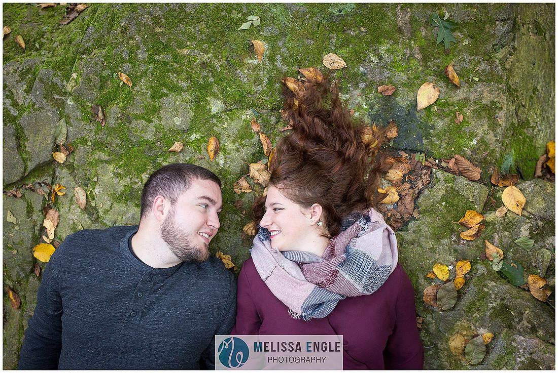 Engagement photo of a couple lying on a mossy rock at Money Rocks County Park.