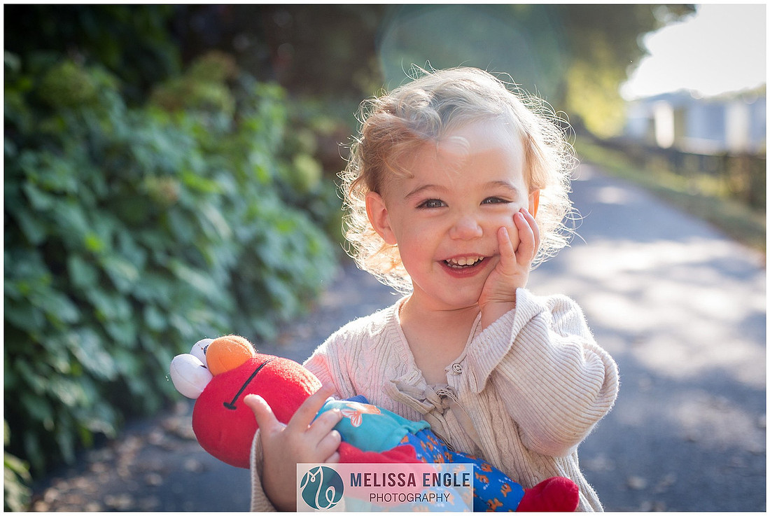 Close up photo of a toddler holding an Elmo doll and laughing by Melissa Engle Photography in Lititz, PA.
