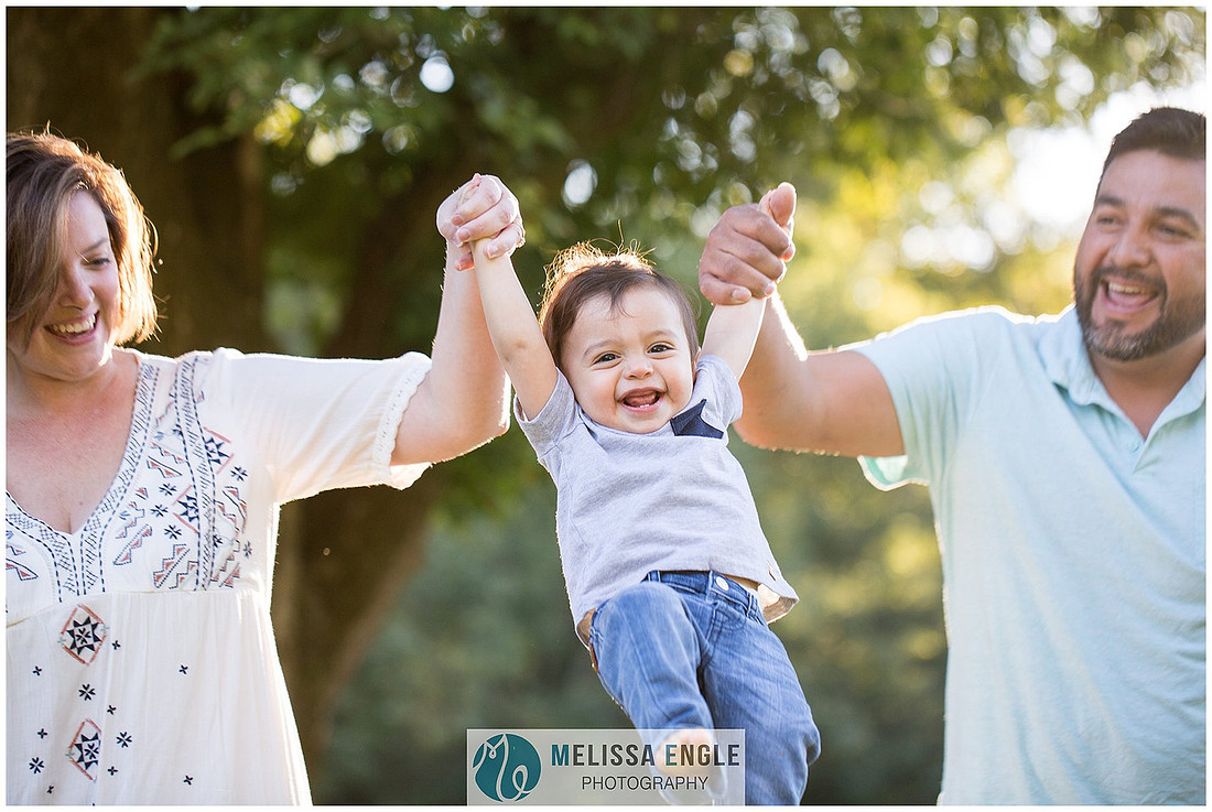 Happy candid photo of a child being swung in the air by his parents.