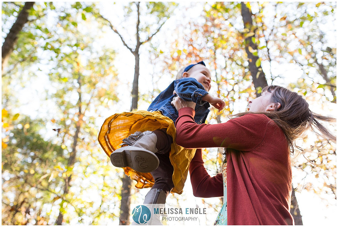 Joyful image of a mother holding her daughter up in the air on a beautiful autumn day in Lancaster, PA.