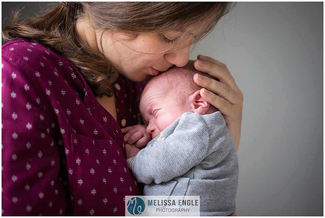 Photo of a mother holding and kissing her newborn baby boy.